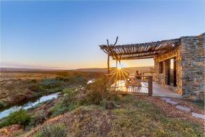 a person standing on a porch of a stone building at Canyon Cottage in Cloeteskraal