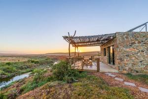 a stone house with a wooden porch and a bridge at Canyon Cottage in Cloeteskraal