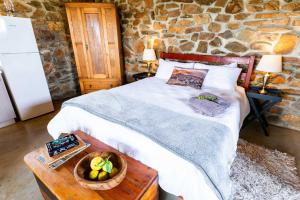 a bedroom with a bed and a stone wall at Canyon Cottage in Cloeteskraal +28 photos