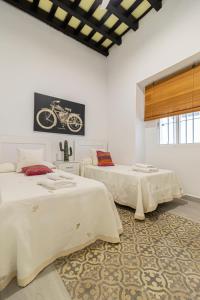 una habitación con 2 camas y una foto de una motocicleta en la pared en Apartamento Santa Clara 1, en Jerez de la Frontera