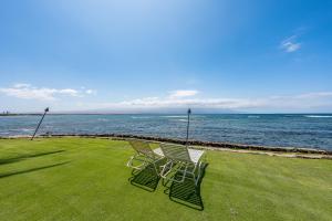 two chairs sitting on the grass next to the water at Oceanfront Condo with Central Location to Kihei & Lahaina in Wailuku