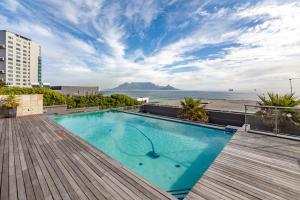 a swimming pool on top of a building with a view of the ocean at Luxury Beachfront Apartment in Blouberg- 1 bedroom in Bloubergstrand