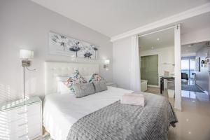 a white bedroom with a large white bed with pillows at Luxury Beachfront Apartment in Blouberg- 1 bedroom in Bloubergstrand +28 photos