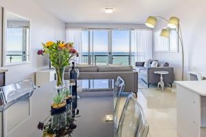 a living room with a couch and a table with flowers on it at Luxury Beachfront Apartment in Blouberg- 1 bedroom in Bloubergstrand