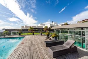 a deck with a swimming pool and a building at Luxury Beachfront Apartment in Blouberg- 1 bedroom in Bloubergstrand