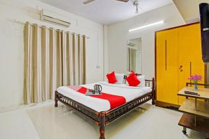 a bedroom with a bed with red pillows and a desk at Hotel O Star in Kharadi