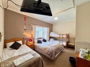 a bedroom with two beds and a tv on the wall at Kendal Hotel in Blackpool