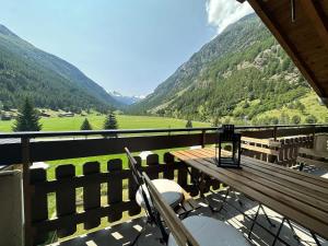 a balcony with a wooden bench and a view of mountains at Majestic View Alpine Retreat in Täsch