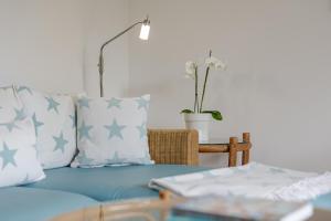 a blue couch with pillows and a table with a plant at Meer in Süderende