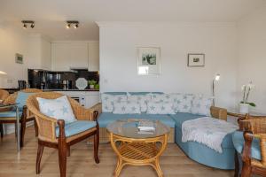 a living room with a blue couch and chairs at Meer in Süderende