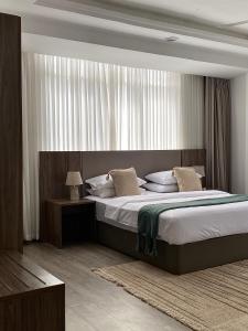 a bedroom with a large bed and a window at Ex Daya Residency in Dar es Salaam