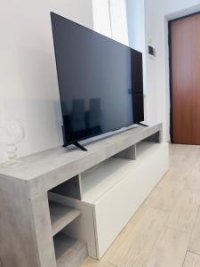 TV de pantalla plana grande en un centro de entretenimiento blanco en Era apartments 2, en Caponago