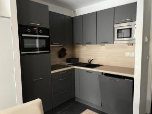 a kitchen with black cabinets and a sink at Résidence Le Portillo - Piscine - Studio pour 4 Personnes MAE-5283 in Gourette