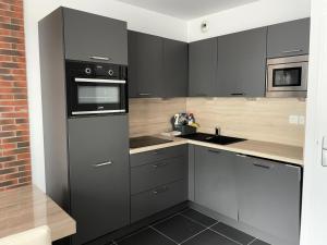 a kitchen with black cabinets and a microwave and a sink at Résidence Le Portillo - Piscine - Studio pour 4 Personnes MAE-5293 in Gourette