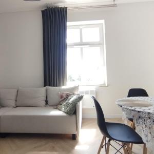 a living room with a couch and a table and a window at Apartment Rozbrat 5 in Wrocław