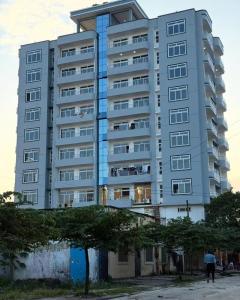 a tall apartment building with a tree in front of it at Ex Daya Residency in Dar es Salaam