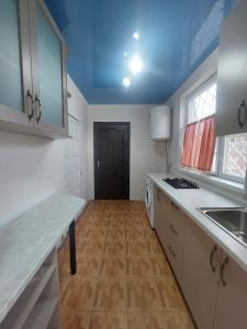 a kitchen with white cabinets and a blue ceiling at Cozy two bedroom house! in Bishkek