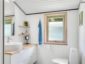 a bathroom with a sink and a toilet and a window at Holiday Home Spasena - 600m from the sea by Interhome in Løkken