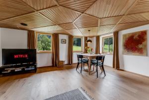 a living room with a table with chairs and a tv at Ferienwohnung Bergblick - stilvoll & modern im Grünen in Grünenbach