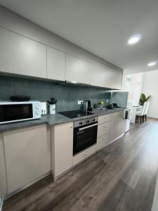 a kitchen with white cabinets and a stove top oven at 4youhouse in Viseu