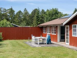ein Tisch und Stühle im Hinterhof eines roten Hauses in der Unterkunft Holiday Home Fritza - 500m from the sea by Interhome in Fårevejle