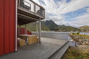 een houten terras met een tafel en banken op een gebouw bij Seahouse with Panoramic Sea View in Ballstad