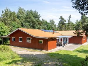 eine rote Scheune mit einem orangefarbenen Dach in der Unterkunft Holiday Home Paulus - 375m from the sea by Interhome in Fårevejle