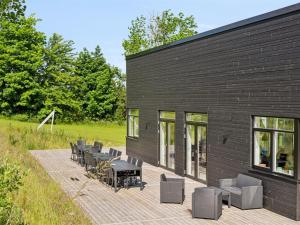 a black building with tables and chairs on a deck at Holiday Home Galatia - 700m from the sea by Interhome in Grenå +29 photos