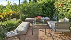 a patio with couches and a glass table and flowers at Bilocale in strada Vestricciano Genna con giardino privato in Perugia