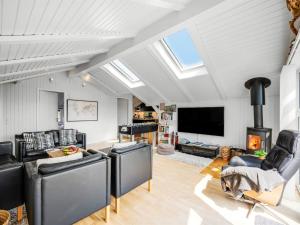 a living room with black leather furniture and a fireplace at Holiday Home Emin - 700m from the sea by Interhome in Vejers Strand