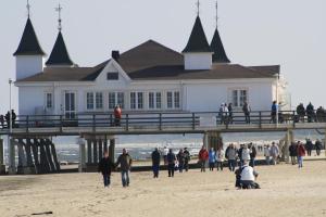 eine Gruppe von Menschen, die am Strand vor einem Gebäude spazieren in der Unterkunft Haus zum Stern in Ahlbeck