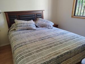 a bed with two pillows on it in a bedroom at Pucón, casa en parcela in Pucón