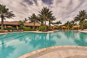 Chic Getaway in Bradenton with Pool Access في Lorraine: حمام سباحة كبير مع أشجار النخيل والمظلات