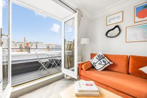 a living room with an orange couch and a large window at Stay Kula London - Covent Garden Maiden Lane in London