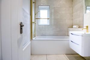 a white bathroom with a tub and a sink at Beautiful and Cosy 4-bed Home in Milton Keynes by Renzo, Driveway, Close to M1 in Milton Keynes +34 photos
