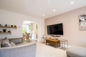 a living room with a couch and a tv on a wall at Beautiful and Cosy 4-bed Home in Milton Keynes by Renzo, Driveway, Close to M1 in Milton Keynes