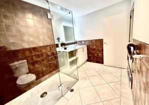 a bathroom with a glass shower and a toilet at Supreme on Marine - Beachfront! in Mount Maunganui +28 photos