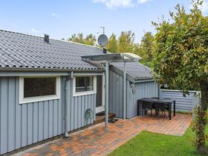 a grey house with a table and a fence at Holiday Home Albertina - 200m from the sea by Interhome in Hals