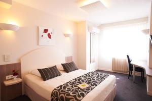 a bedroom with a bed and a table and a desk at Logis Auberge de la Rose in Doué-la-Fontaine