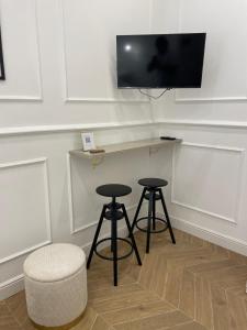 a bar with two stools and a tv on a wall at Fronte Reggia Apartment in Caserta