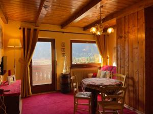 een eetkamer met een tafel en stoelen en een raam bij Rifugio romantico per due in Pinzolo