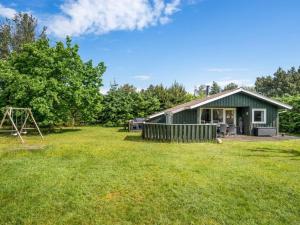 a green house with a playground in the yard at Holiday Home Myrna - 300m from the sea by Interhome in Hals