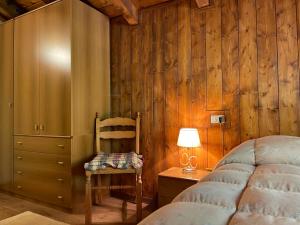 een slaapkamer met een bed, een stoel en een bureau bij Rifugio romantico per due in Pinzolo