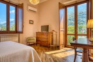 Un dormitorio con una cama, un escritorio y ventanas. en La Baronessa Apartment near Pompei & Amalfi Coast, en Angri