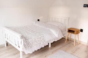 a white bedroom with a white bed and a wooden table at StyLove Domki 1 in Kluszkowce +34 photos