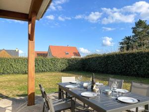 a table with plates and wine glasses on a patio at Maison Belle Étoile à 5 min de la plage in Les Moitiers-dʼAllonne