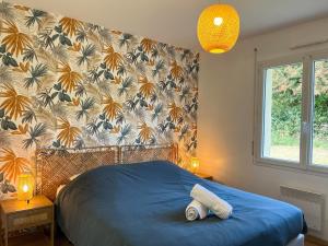 a bedroom with a bed with a blue comforter at Maison Belle Étoile à 5 min de la plage in Les Moitiers-dʼAllonne