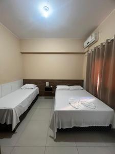 a hospital room with two beds and a light at Hotel Pinheiro in Unaí