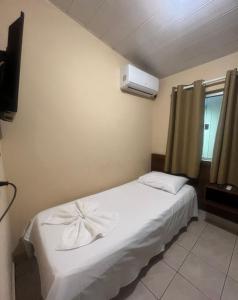 a bedroom with a white bed and a air conditioner at Hotel Pinheiro in Unaí