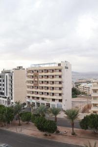 a large white building with palm trees in front of it at Mariam Aqaba Hotel in Aqaba